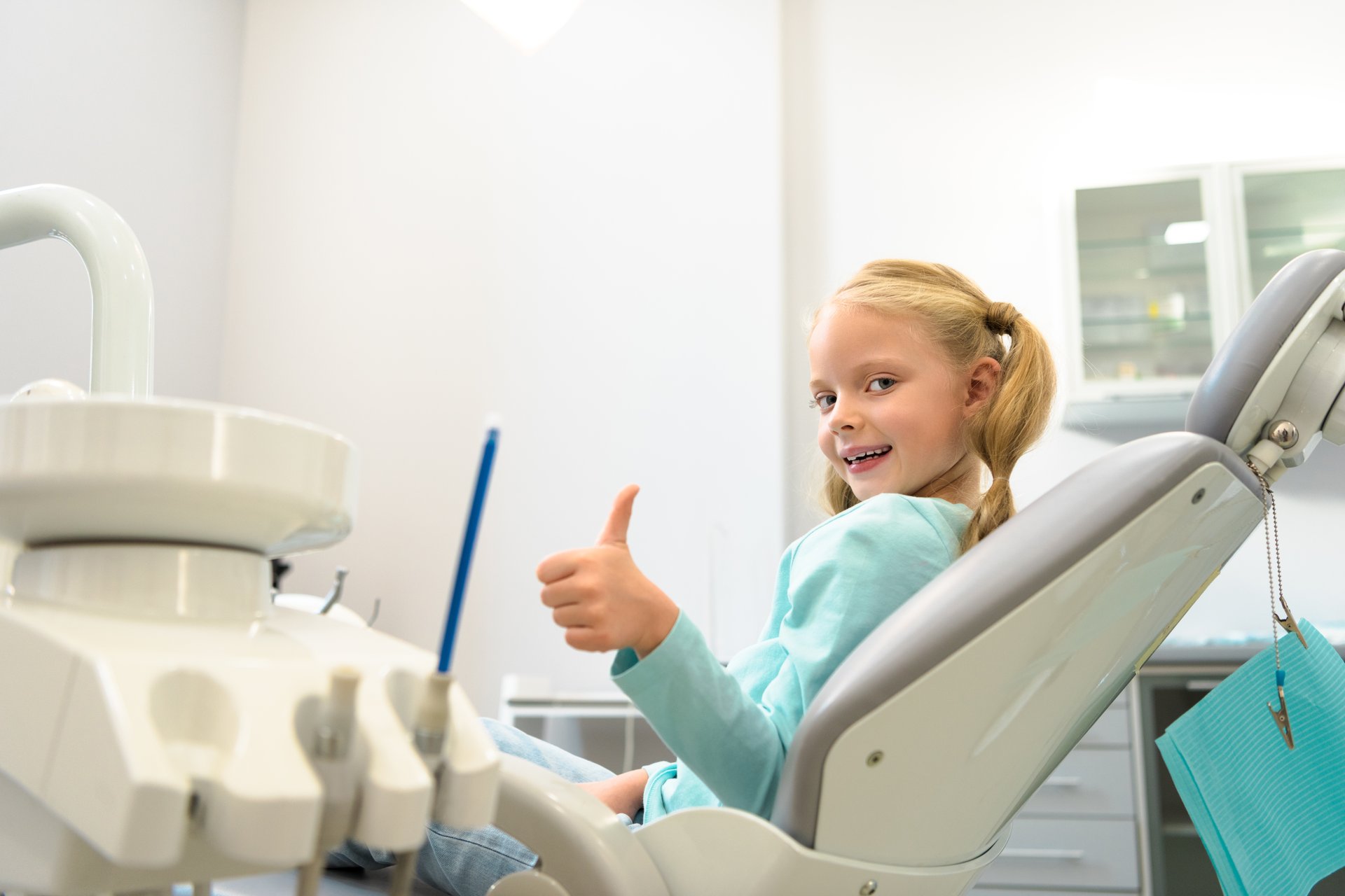 A young man with a concerned expression is seated in a dental chair while receiving dental care from a professional, who appears to be a dentist.