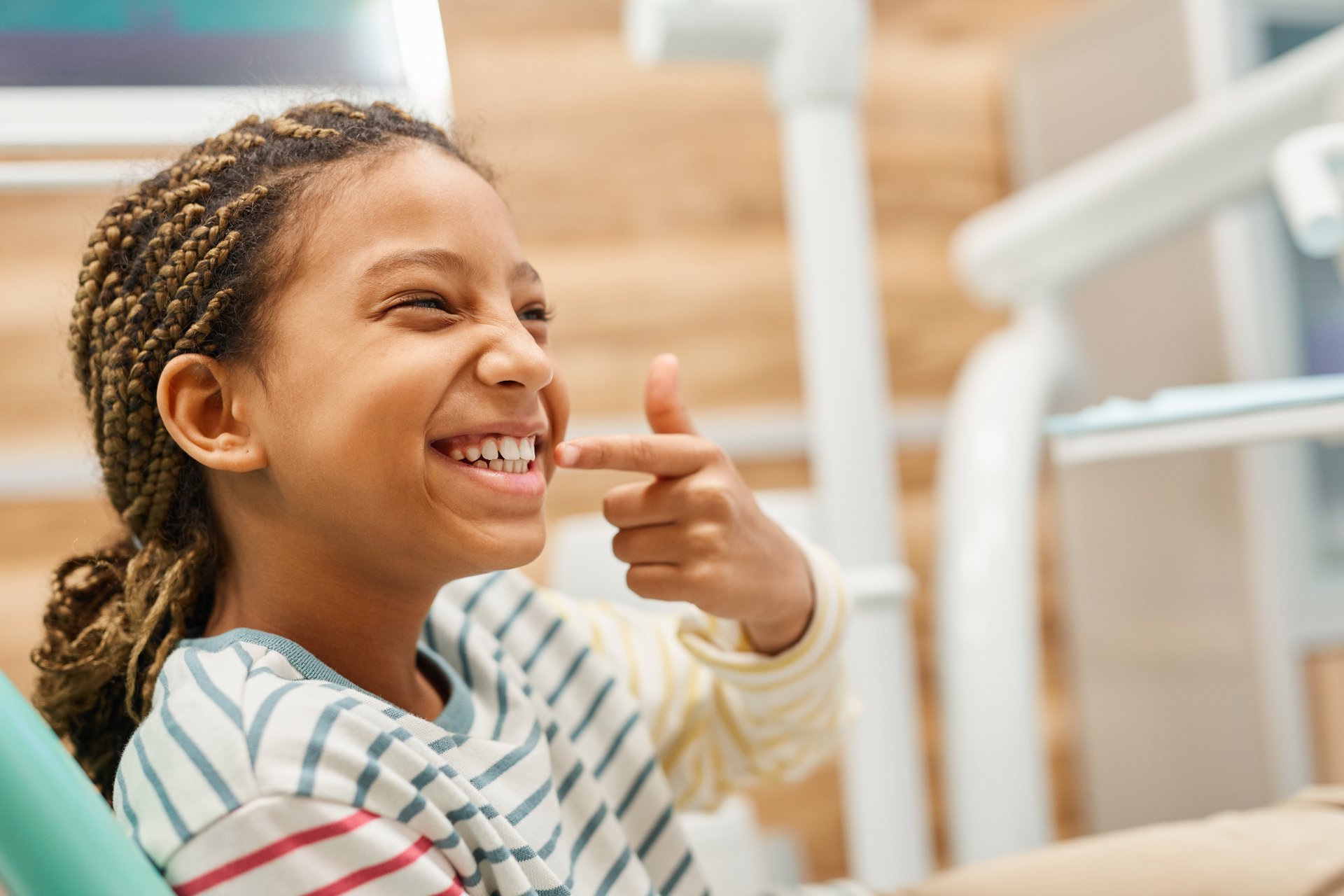 A young child with a joyful expression, making a fist with both hands and standing against a neutral background.
